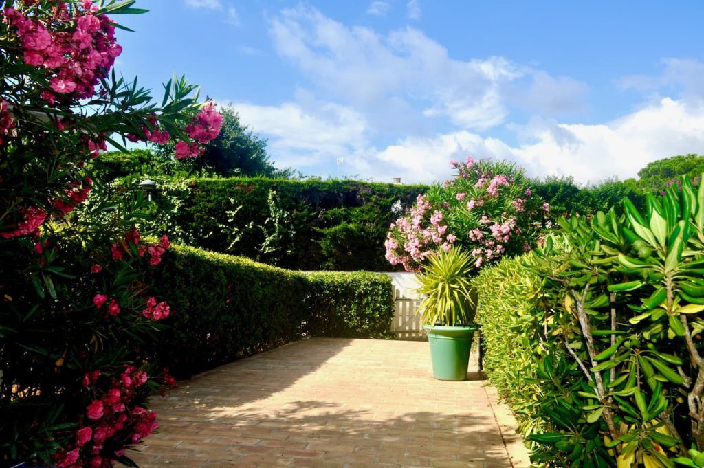 Jardin privatif dallé entouré de haies et de lauriers-roses — appartement Dalí, La Fosca Bay (Palamós, Costa Brava)