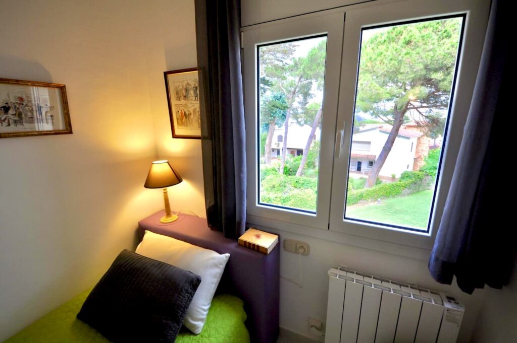Schlafzimmer mit Einzelbett und Blick in den Garten — Ferienwohnung Miró, La Fosca Bay (Palamós, Costa Brava)