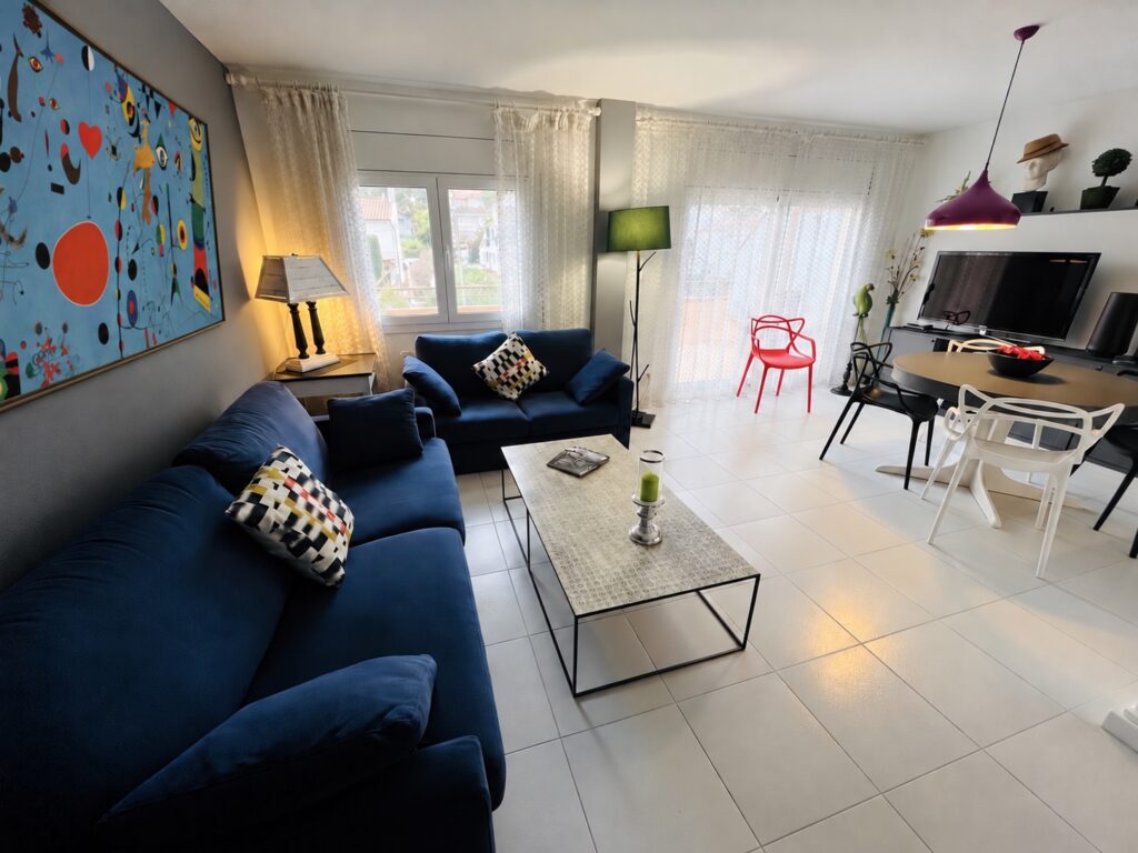 Salon avec canapés bleus et coin repas — appartement Miró, La Fosca Bay (Palamós, Costa Brava)