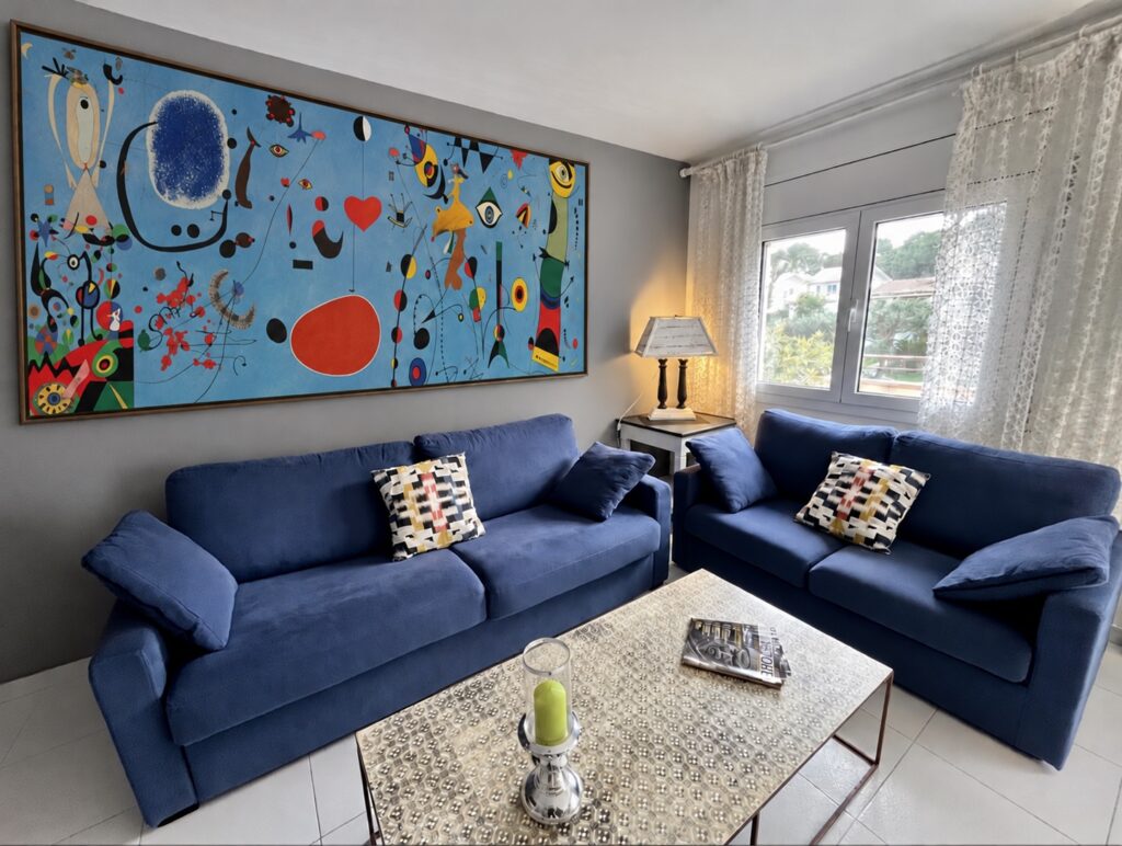 Salon aux canapés bleus et tableau de Miró — appartement Miró, La Fosca Bay (Palamós, Costa Brava)